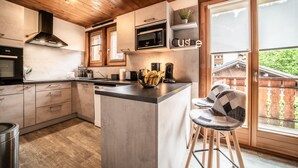 Een moderne keuken met houten kastjes, een centraal eiland, een magnetron en een koffieapparaat.