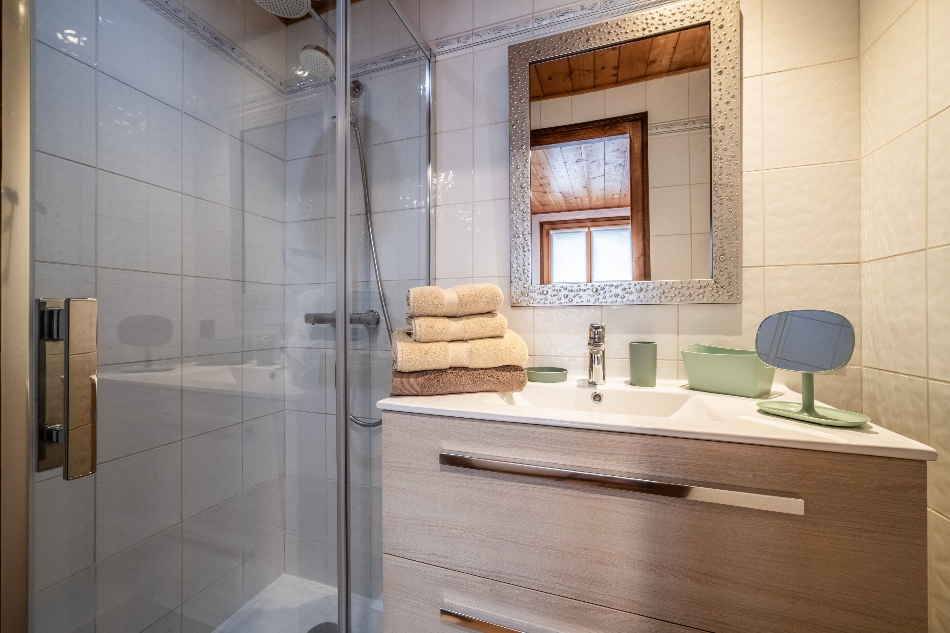 A modern bathroom with a glass shower enclosure, a vanity with a mirror, and a sink.