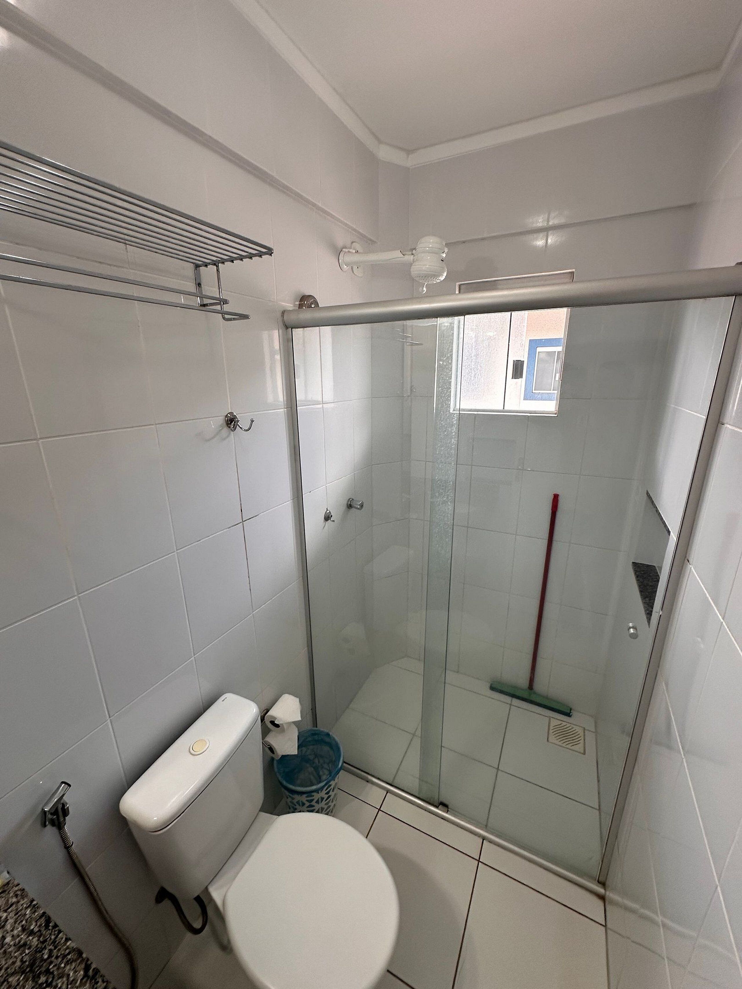 Un baño con inodoro, ducha con puerta de cristal y ventana.