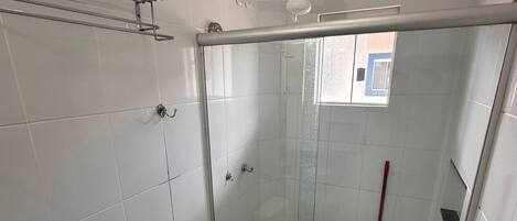 Un baño con inodoro, ducha con puerta de cristal y ventana.