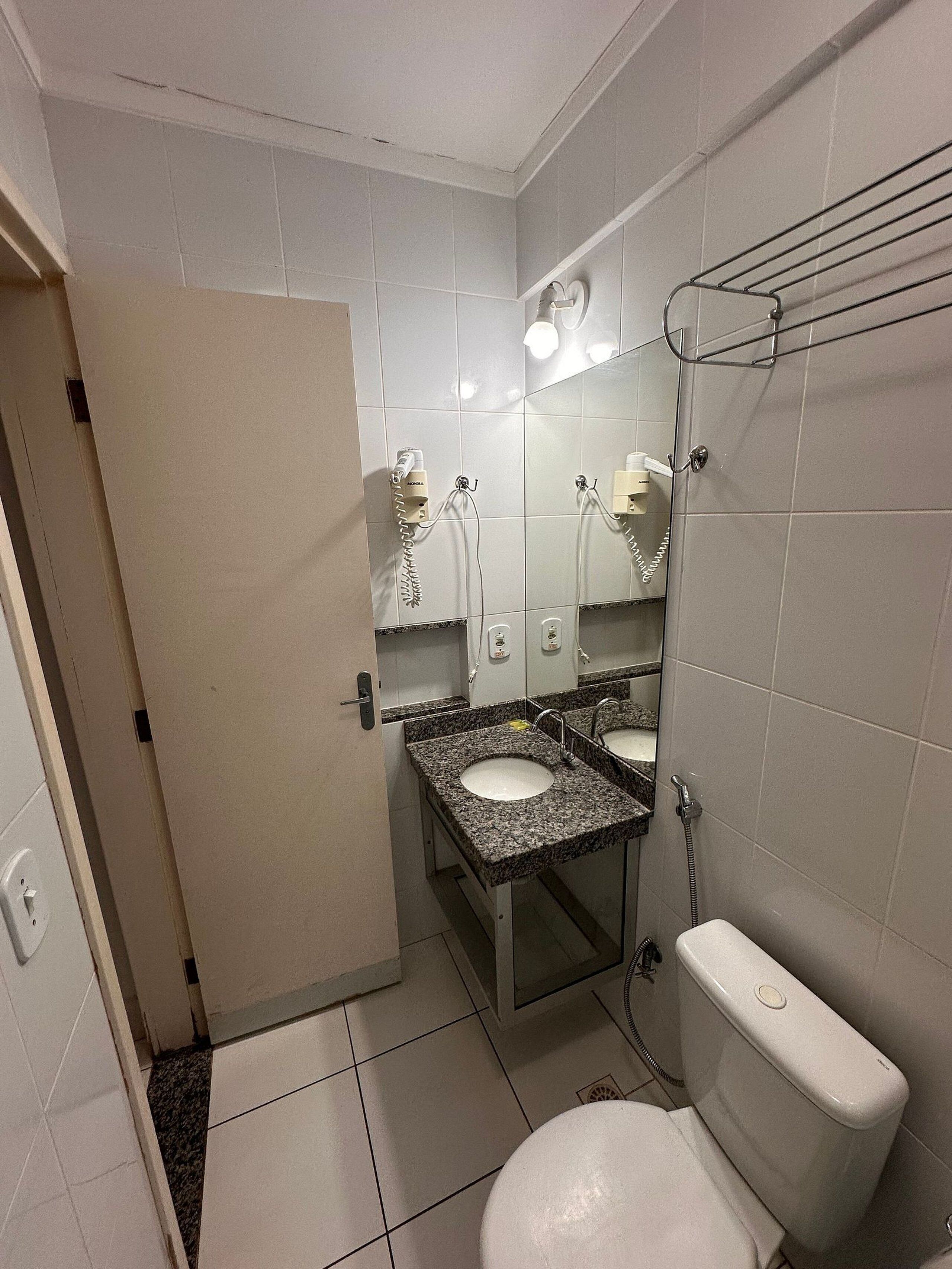 A small bathroom with two sinks, a toilet, and a shower.