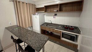Una cocina compacta con encimera de granito, horno integrado y refrigerador.
