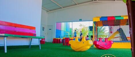 A children's play area with a bench, play structures, and a netted climbing area.