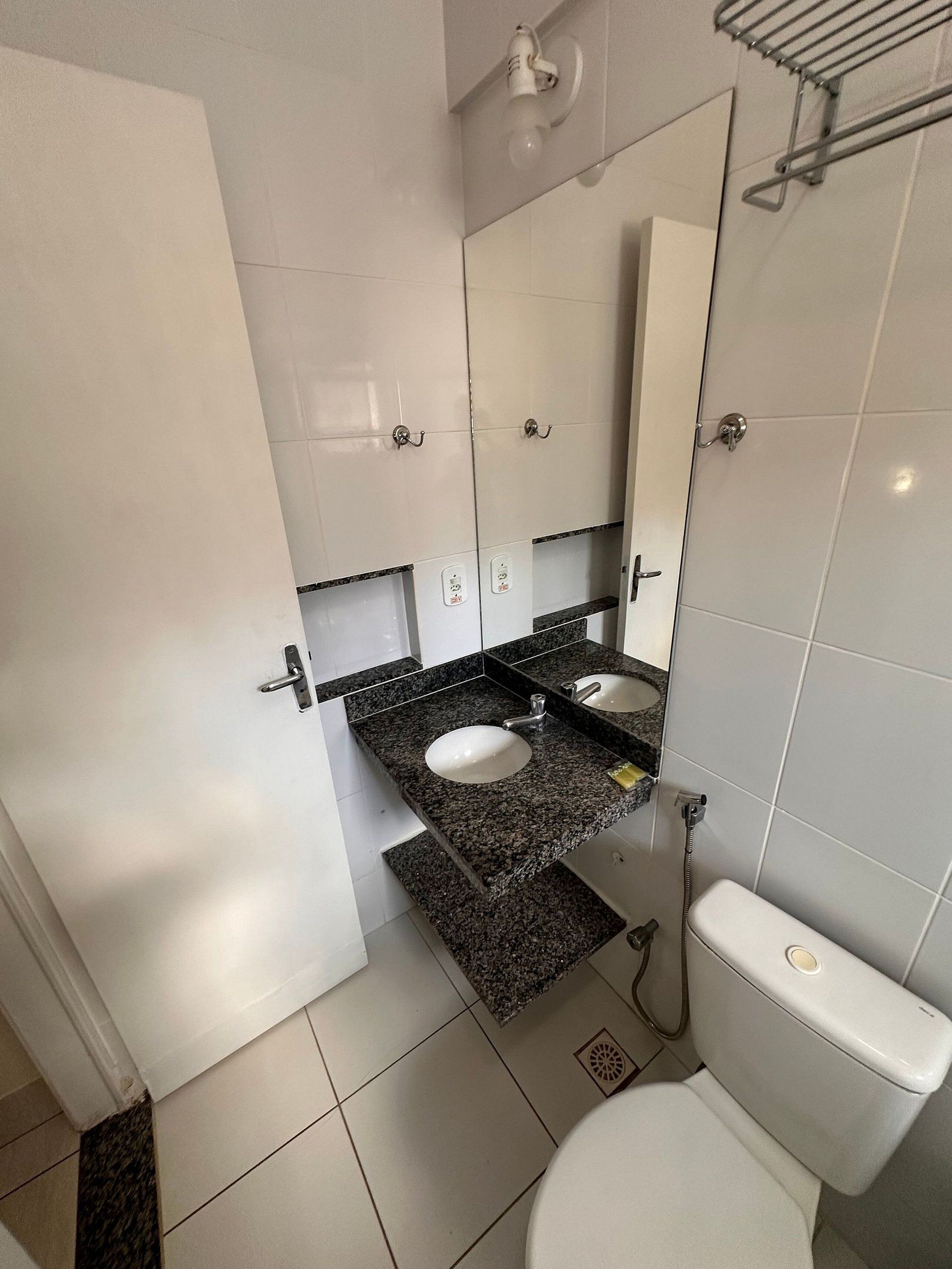 A bathroom with two sinks, a toilet, and a mirror.