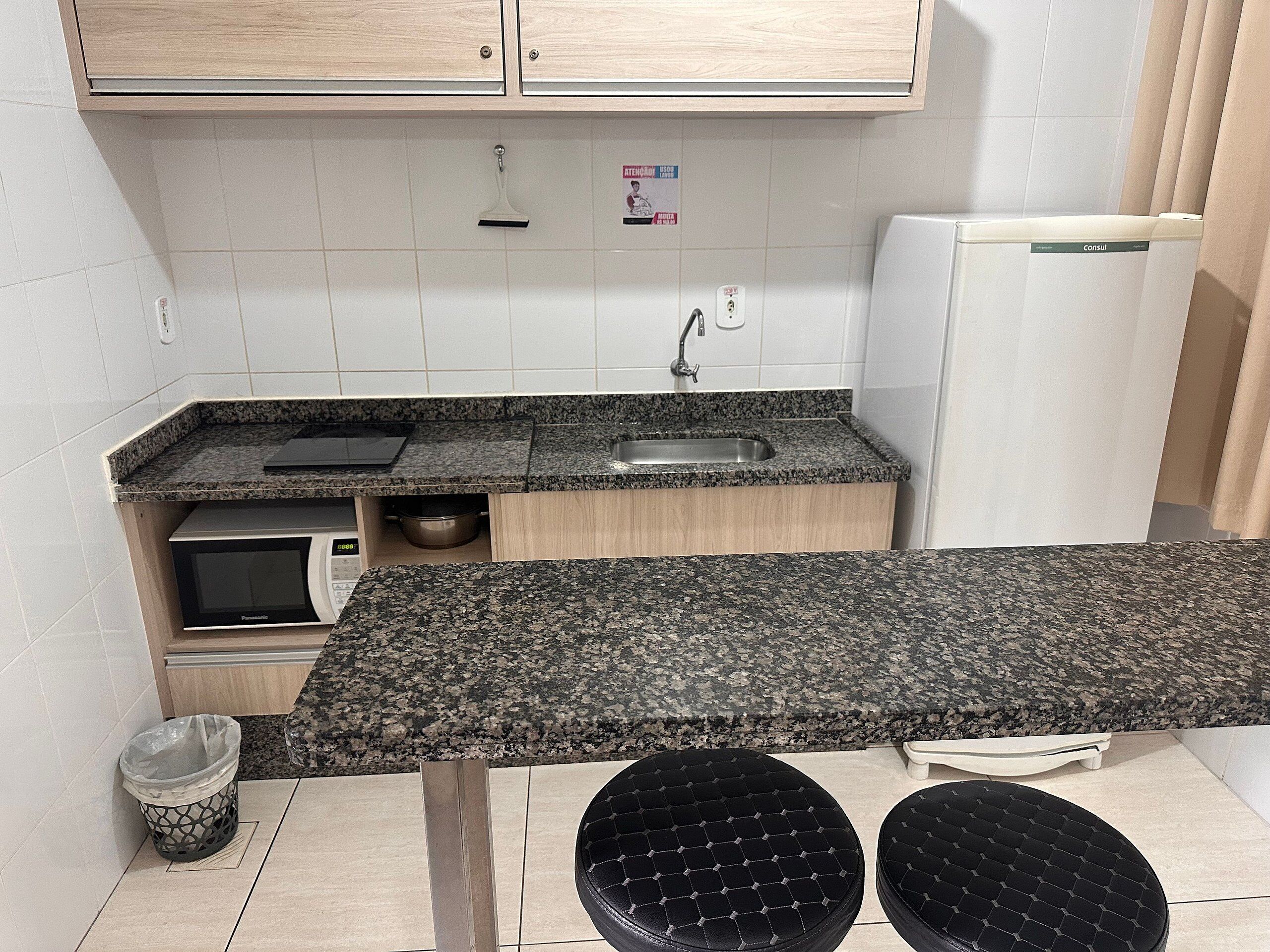 A kitchen with a granite countertop, a sink, a microwave, and a refrigerator.
