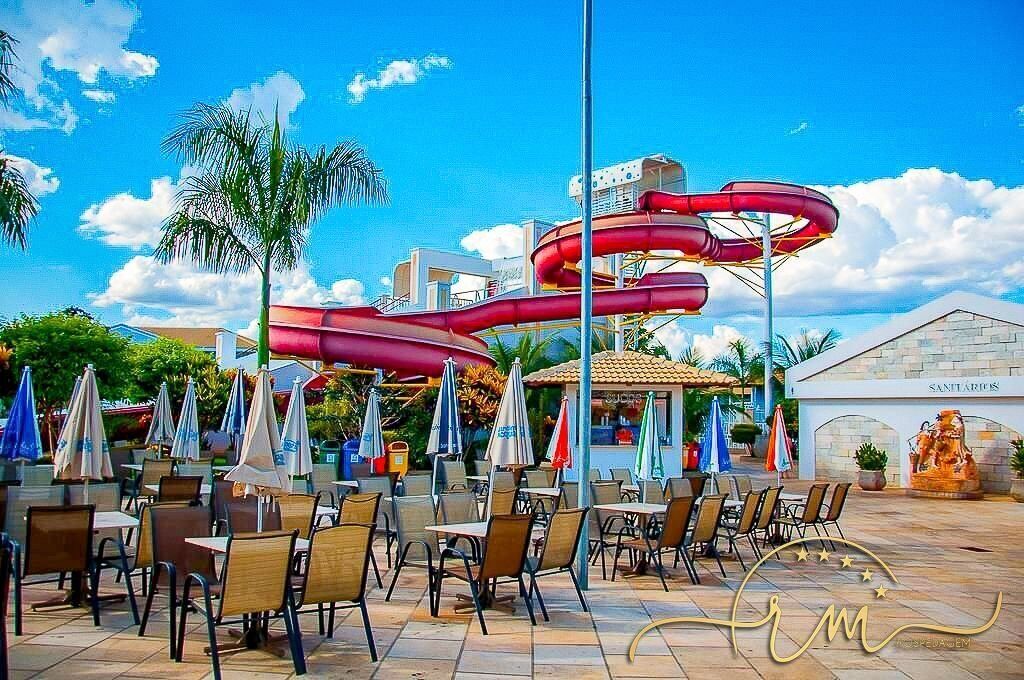 Un espace extérieur doté d’un toboggan aquatique, de sièges en plein air et d’un bâtiment portant l’inscription « SANITARIAS ».