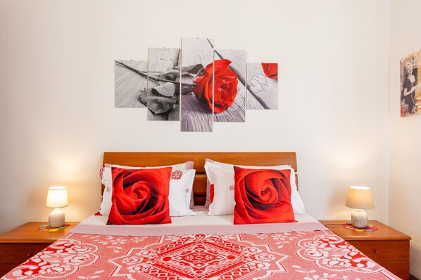 A neatly arranged hotel room with a bed, two bedside tables, and a wall-mounted artwork of a rose.