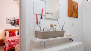 Un dormitorio moderno con cama, mesita de noche y una consola blanca con objetos decorativos.