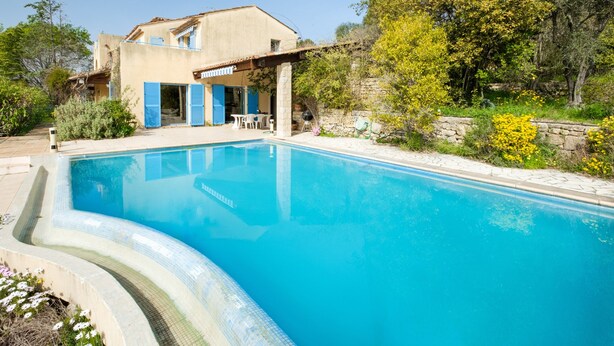 Una piscina con una casa al fondo.