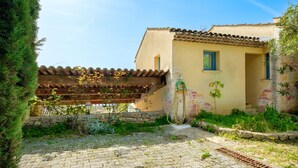 Una casa con techo de tejas, pared de piedra y jardín con manguera.