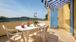 Una terraza con una mesa y sillas, un toldo a rayas y una puerta azul.