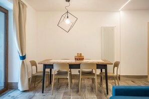 Een eetruimte met een houten tafel, zes stoelen, een hanglamp en een radiator.
