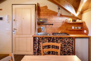 A compact kitchen with a wooden countertop, a sink, a gas stove, and a patterned tablecloth.