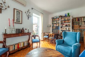 A living room with a bookshelf, a dining table, and a blue armchair.