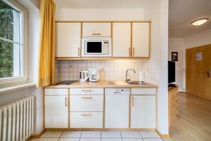 Een moderne keuken met witte kastjes, een magnetron, een koffiezetapparaat en een vaatwasser.