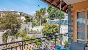 Ein Balkon mit Tisch für zwei Personen, einer Kaffeekanne und einem Blumenvasen.
