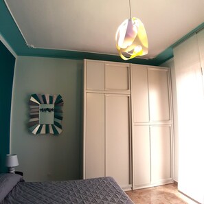 Una camera da letto con un letto, un armadio e uno specchio fissato alla parete.