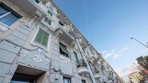 A historic building with ornate architectural details, including decorative moldings and a balcony with a wrought iron railing.