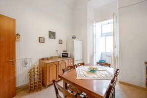 Une cuisine avec une table en bois, des chaises, un four à micro-ondes, un réfrigérateur et une fenêtre.