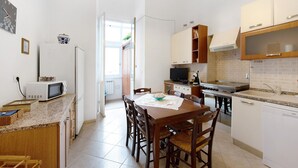 A compact kitchen with a dining table, chairs, a microwave, stove, and cabinets.