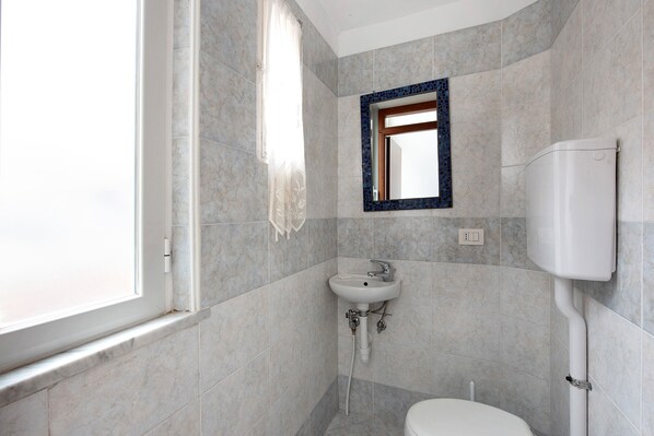 Ein Badezimmer mit Fenster, Waschbecken und Toilette.
