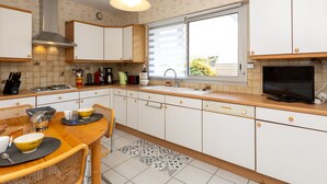 Een moderne keuken met witte kasten, een gasfornuis, een spoelbak en een raam dat natuurlijk licht binnenlaat.
