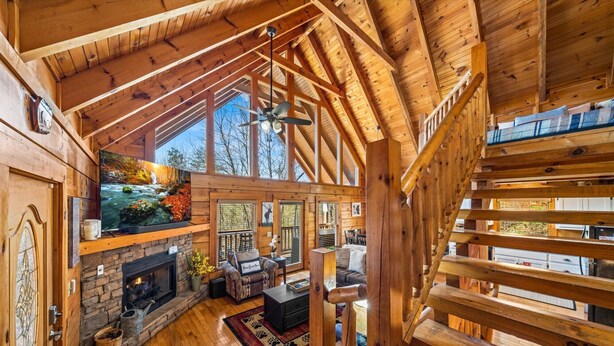 L’intérieur de cette vaste cabane en rondins est agrémenté d’une cheminée en pierre, d’un coin salon confortable et d’une grande fenêtre offrant une vue sur l’extérieur.
