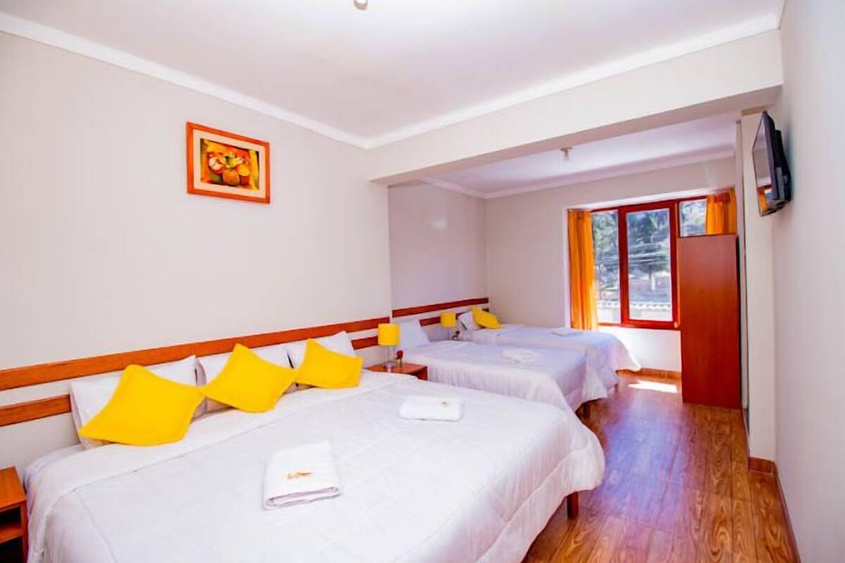 A hotel room with two beds, wooden headboards, white bedding, and a framed picture on the wall.