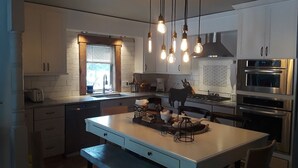 A modern kitchen with white cabinets, a central island, and hanging light fixtures.