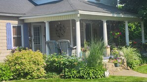 A two-story house with a covered porch, a front door, and a small garden area with plants and a lawn.
