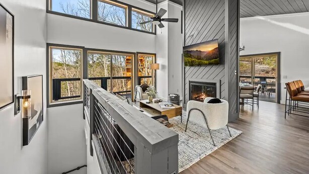 Un espacio habitable amplio con ventanas grandes, una chimenea y un techo alto.