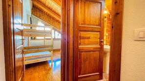 A wooden door with a light switch, a wooden staircase, and a bunk bed.