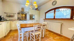 A kitchen with white cabinets, a wooden dining table, and a chandelier.