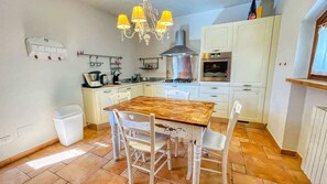 A kitchen with a wooden table, white chairs, a chandelier, and white cabinets.