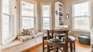Una habitación acogedora con un banco empotrado, una mesa redonda con taburetes y una estantería.