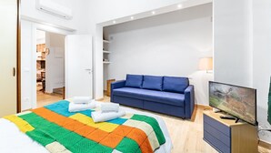 Un dormitorio con una cama, un sofá azul, un televisor y un armario.