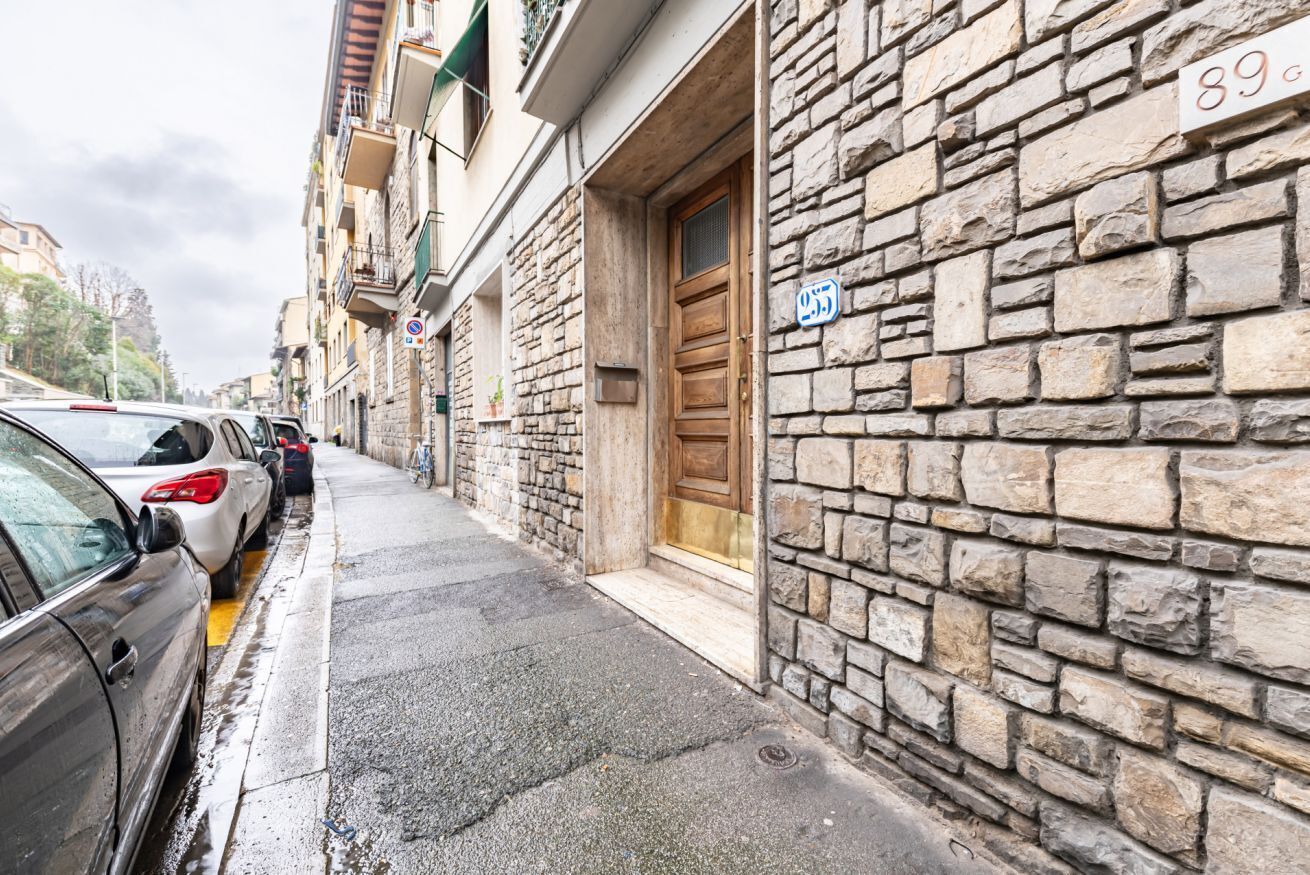 Una calle estrecha con coches estacionados, edificios de piedra y una puerta de madera.