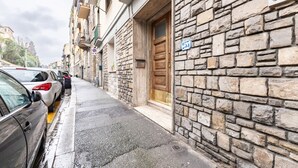 Una calle estrecha con coches estacionados, edificios de piedra y una puerta de madera.