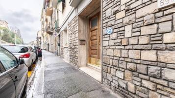 Una calle estrecha con coches estacionados, edificios de piedra y una puerta de madera.