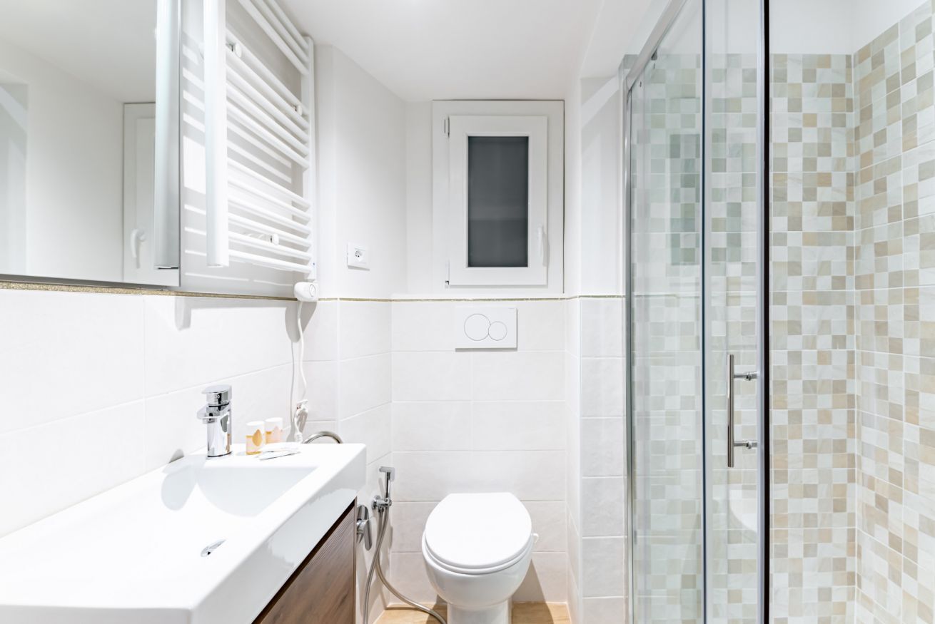 Une salle de bain moderne avec un lavabo, des toilettes et une zone de douche, le tout de couleur blanche.