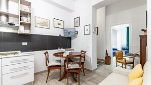 Una cocina moderna con comedor, muebles blancos y un televisor de pantalla plana.