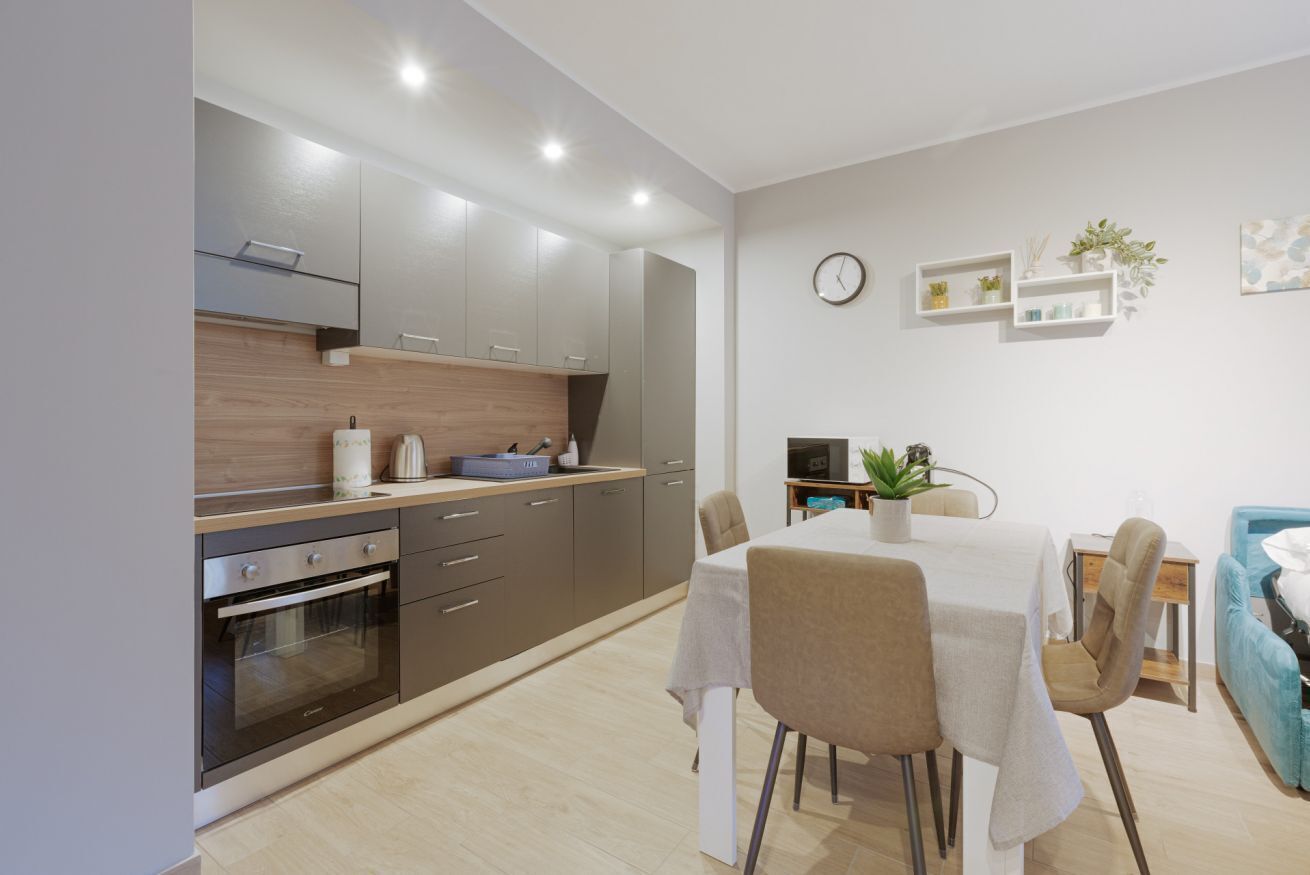 Une cuisine moderne dotée d’appareils électroménagers intégrés, un coin repas avec une table et des chaises, et un petit espace salon avec un canapé.