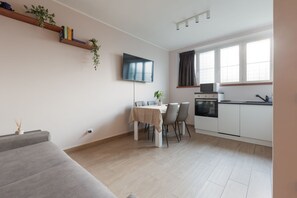 A modern kitchen with a dining area, a flat-screen TV, and a sofa. - GuestHost - Comfortable and modern 45sqm apartment, able to comfortably accommodate up to 4 people, located in the basement of a building WITHOUT a lift (steps to access it). The apartment is located in a strategic position, just a 5-minute walk from the (Milan)