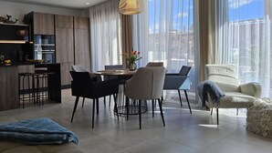 A modern living room with a dining area, large windows, and a kitchen with built-in appliances. - Benidorm eudaimonia by Interhome (Benidorm)