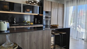 A modern kitchen with a central island, built-in appliances, and a large window with sheer curtains. - Benidorm eudaimonia by Interhome (Benidorm)