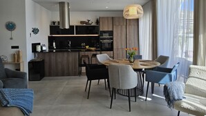 A modern living room with a round dining table, two sofas, and a kitchen in the background. - Benidorm eudaimonia by Interhome (Benidorm)