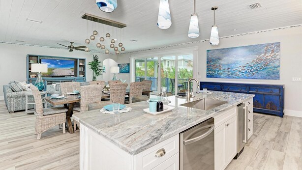 A spacious kitchen with a marble countertop, modern pendant lights, and a large island. - No R-Egrets:1 Block to Beach! Pool Game Room by Anna Maria Life Vacation Rentals (Holmes Beach)