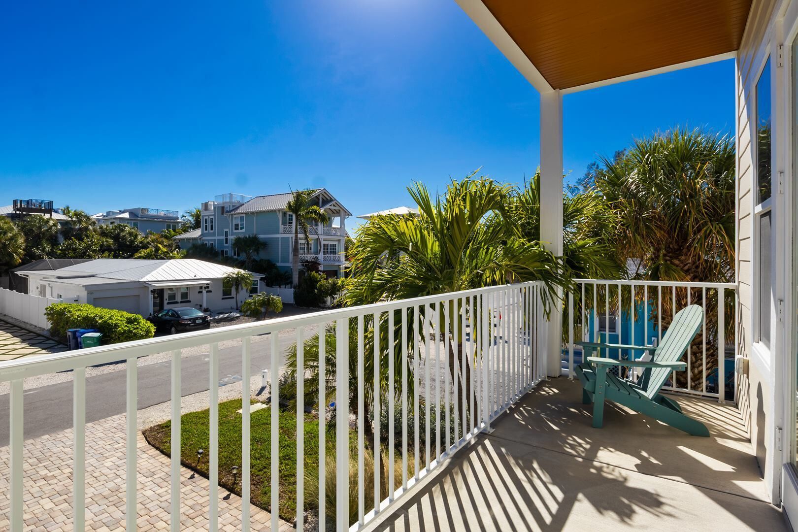 Un balcón con vista a una zona residencial, con casas y palmeras.