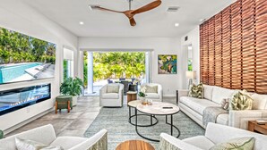 A spacious living room with a pool, a ceiling fan, and a wooden wall. - Tamiami Vice - Luxury Siesta Key Home with Heated Pool & Prime Location – Book Your Escape Today! (Sarasota)