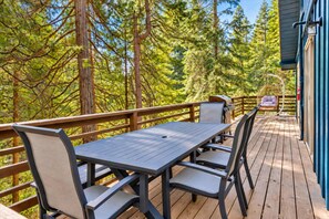 A deck with a table and chairs, surrounded by trees.